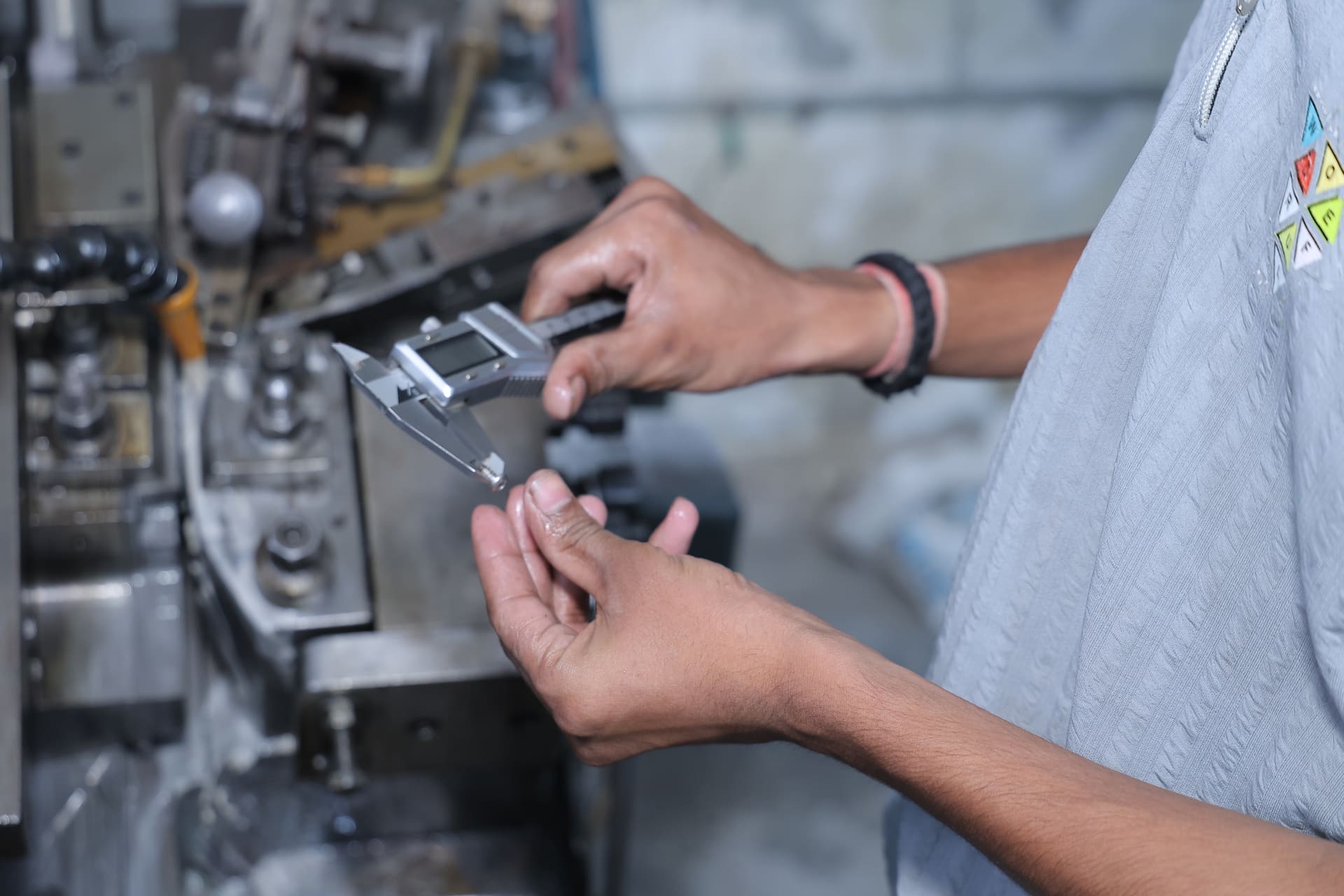 Close-up of a digital caliper measuring a stainless steel screw during quality inspection