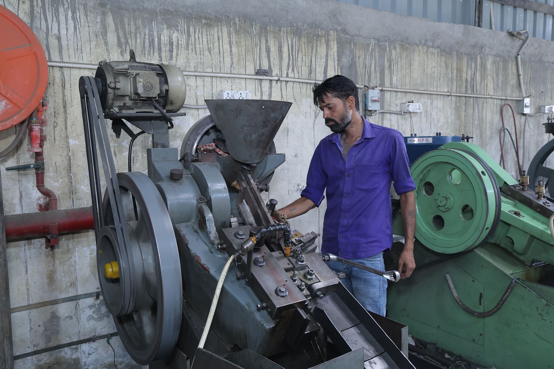 Worker operating a cold heading machine at the Aggarwal Industries manufacturing facility